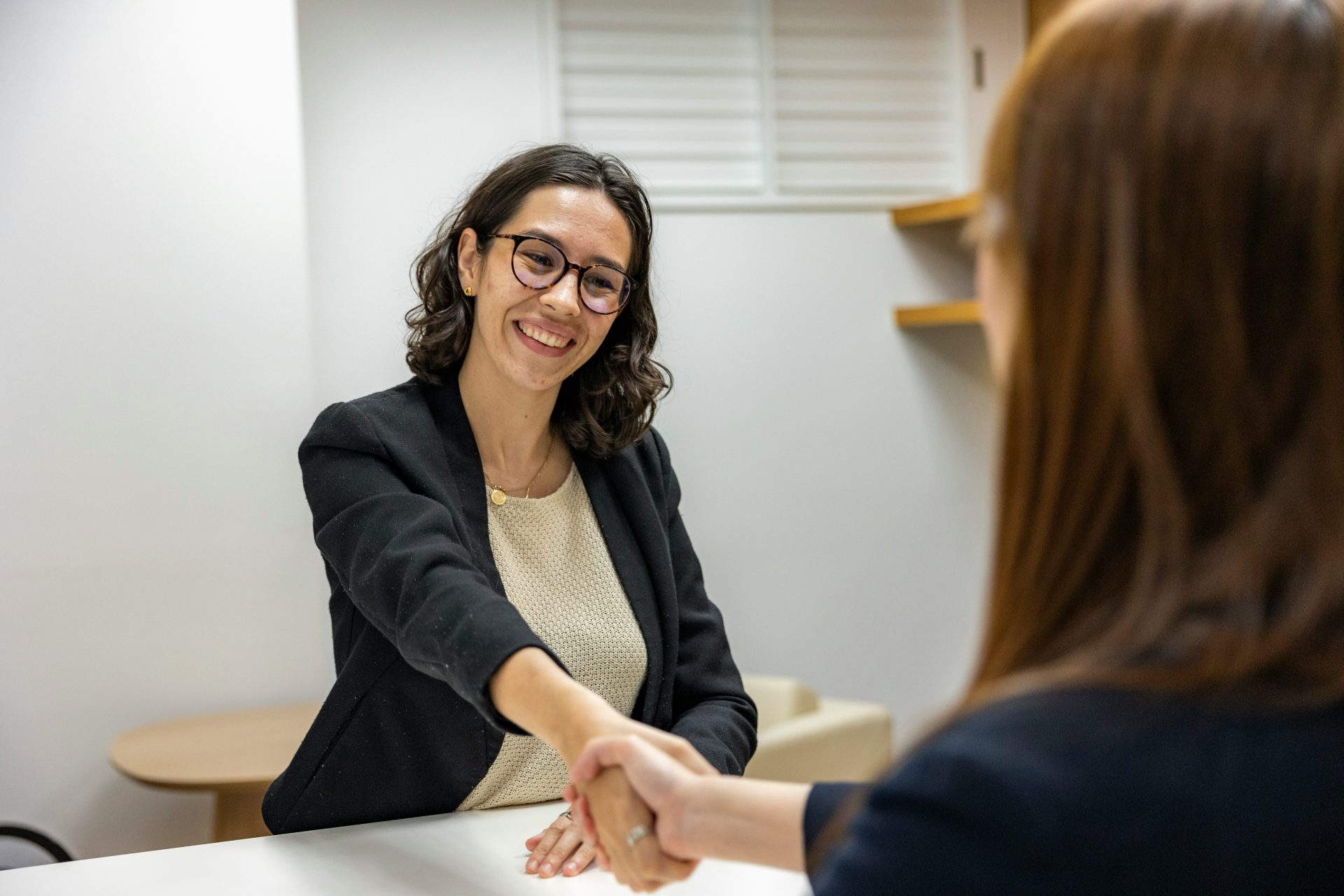 Une femme serrant la main d'une autre femme assise à une table.
